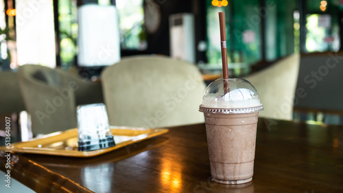 Cocoa Smoothie in glass on wooden table with blur interior coffee shop. snack drink and food in restaurant concept.