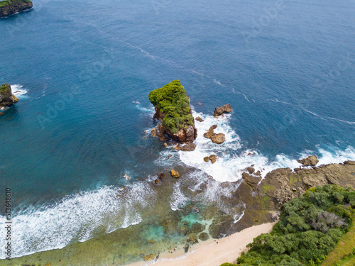 Coral Island which overgrown by trees on the beach and hit by the wave.the sea water looks clear and blue. Jungwok Beach, Yogyakarta, Indonesia photo