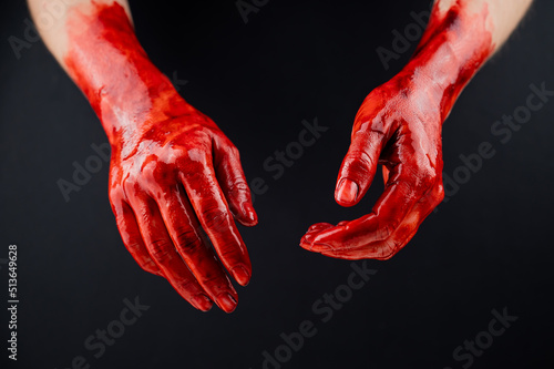 Women's hands in blood on a black background.