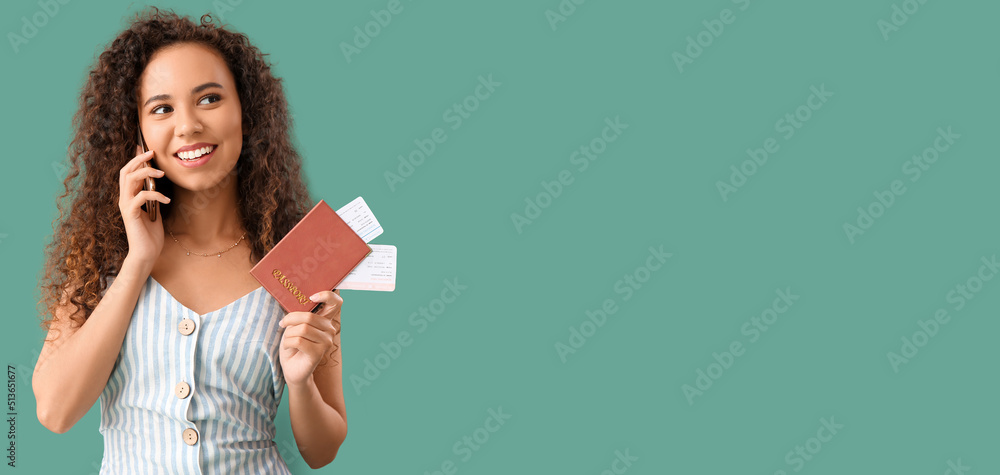 Young African-American woman with passport and tickets talking by mobile phone on green background with space for text Young African-American woman with passport and tickets talking by mobile phone on green background with space for text