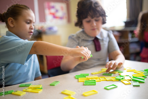 Two primary girl students collaborating with coloured word tiles