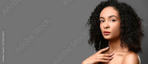 Portrait of beautiful African-American woman on grey background with space for text