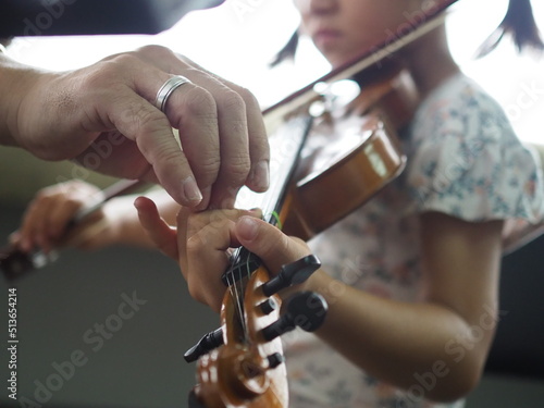 Fototapeta Close up hands of little girl and teacher on violin lesson in the room