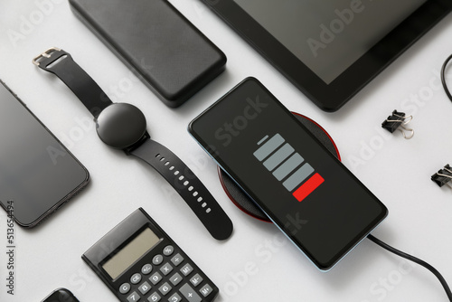 Modern gadgets with uncharged mobile phone and calculator on grey background, closeup