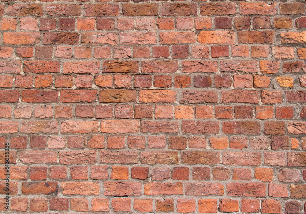 Fototapeta premium Old exterior European brick wall texture background in an English bond brickwork pattern, with weathered bricks in varying shades of red