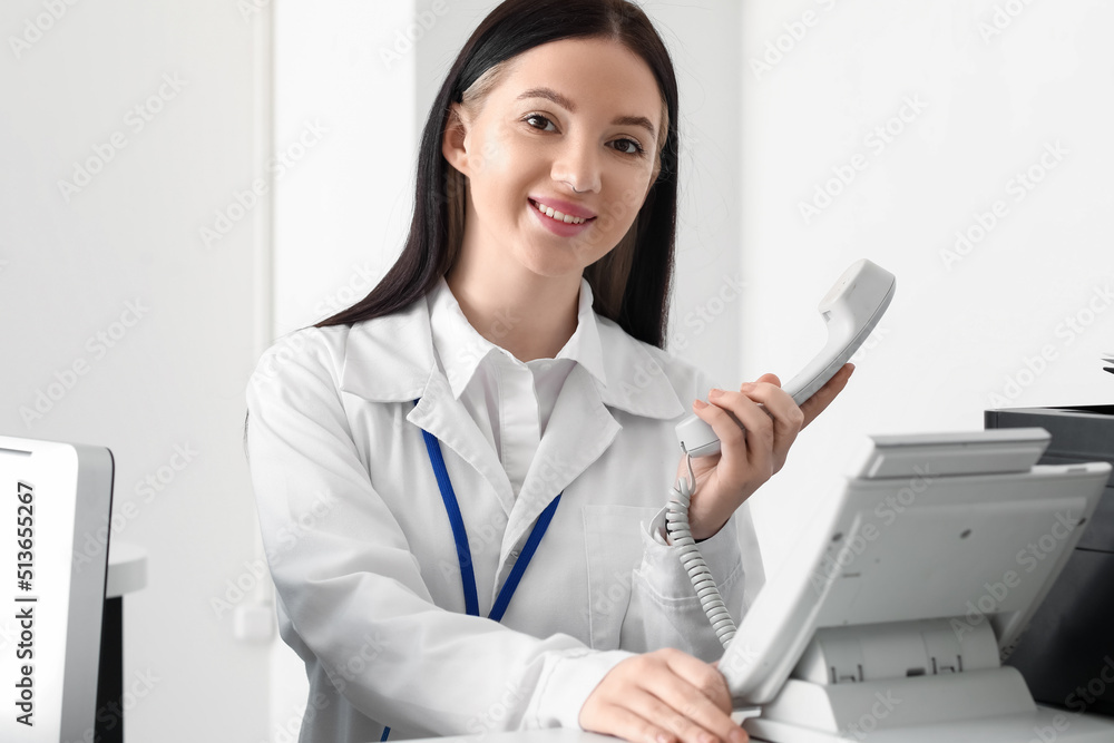 Female receptionist with telephone working in clinic Female receptionist with telephone working in clinic