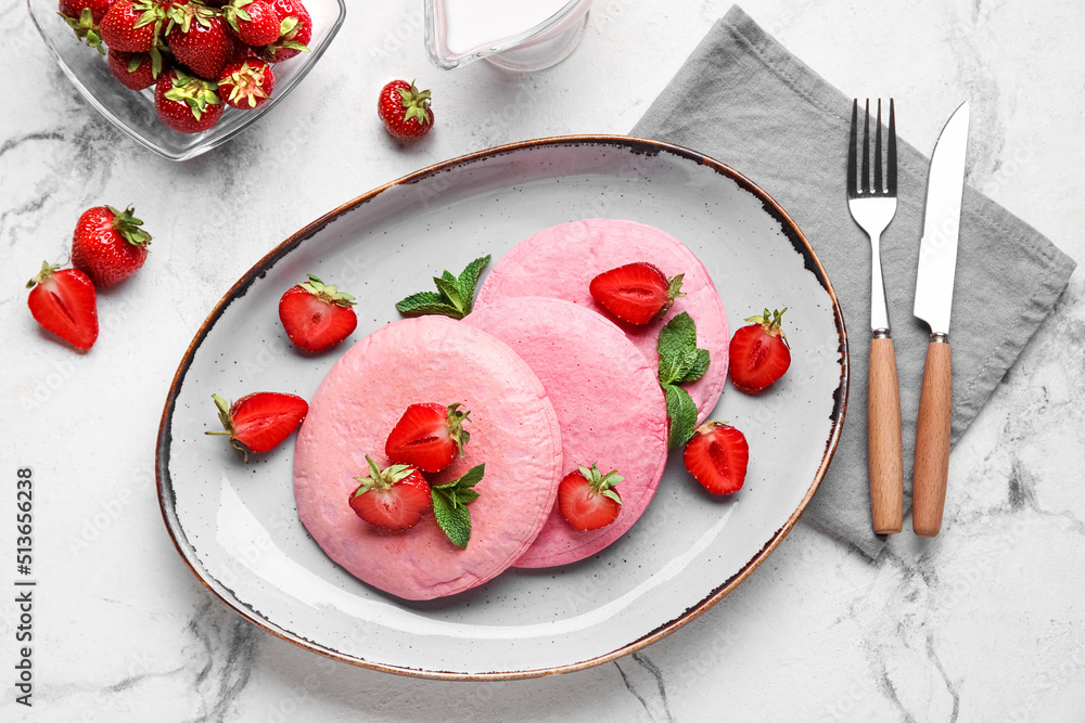 Plate with pink pancakes and strawberry on light background Plate with pink pancakes and strawberry on light background
