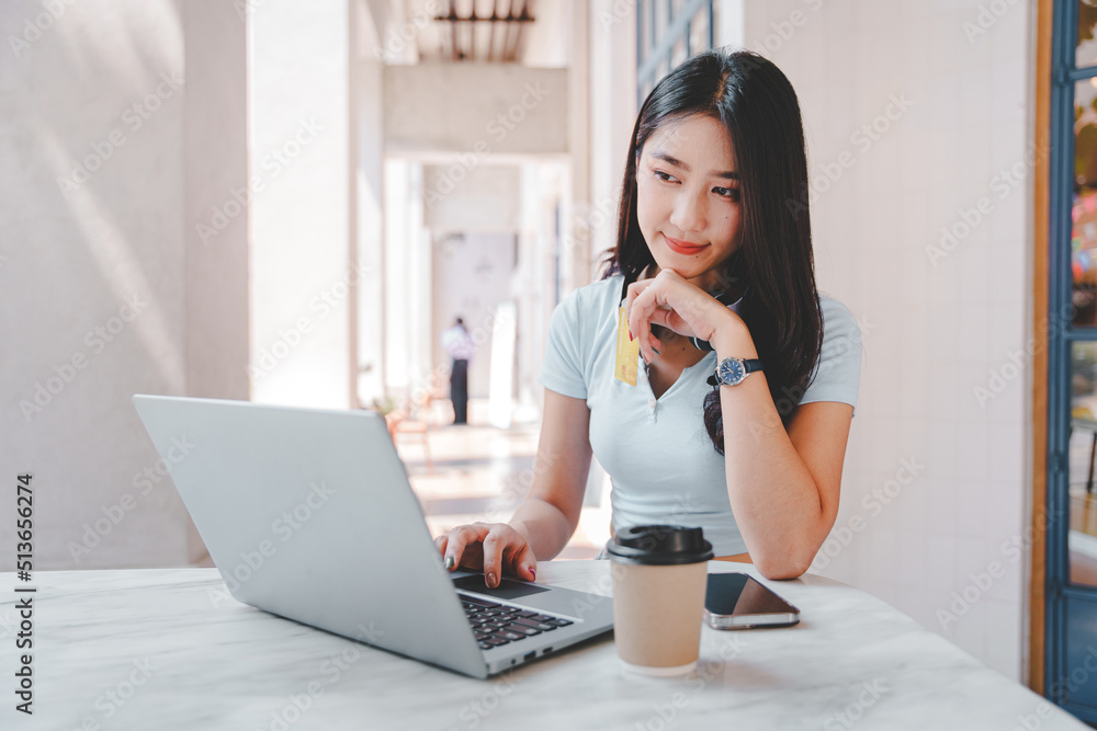 Asian woman holding a credit card and using a laptop computer Businesswoman working at modern office, online shopping, ecommerce, internet banking, spending money, credit card working concept. Asian woman holding a credit card and using a laptop computer Businesswoman working at modern office, online shopping, ecommerce, internet banking, spending money, credit card working concept.