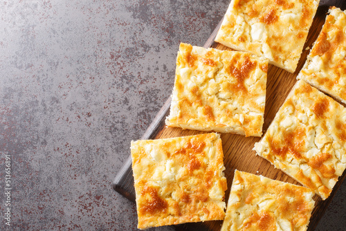 Greek traditional cheese pie with feta close-up on a wooden board on the table. horizontal top view from above photo