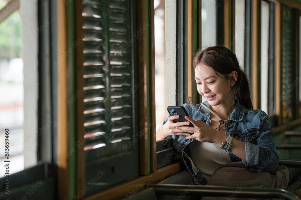 Young Asian woman traveler using smartphone in train. 