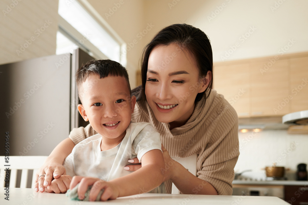 Smiling mother teaching son cleaning table after dinner Smiling mother teaching son cleaning table after dinner