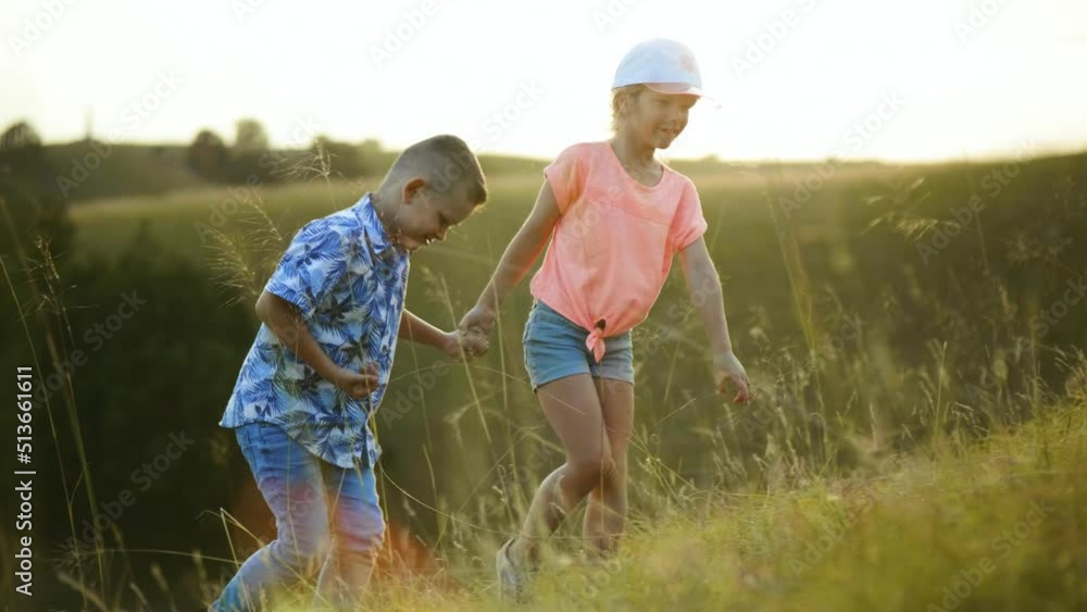 Happy brother and sister climb the hill on nature on trekking trip and look forward to a successful arrival at the finish line at sunset Happy brother and sister climb the hill on nature on trekking trip and look forward to a successful arrival at the finish line at sunset