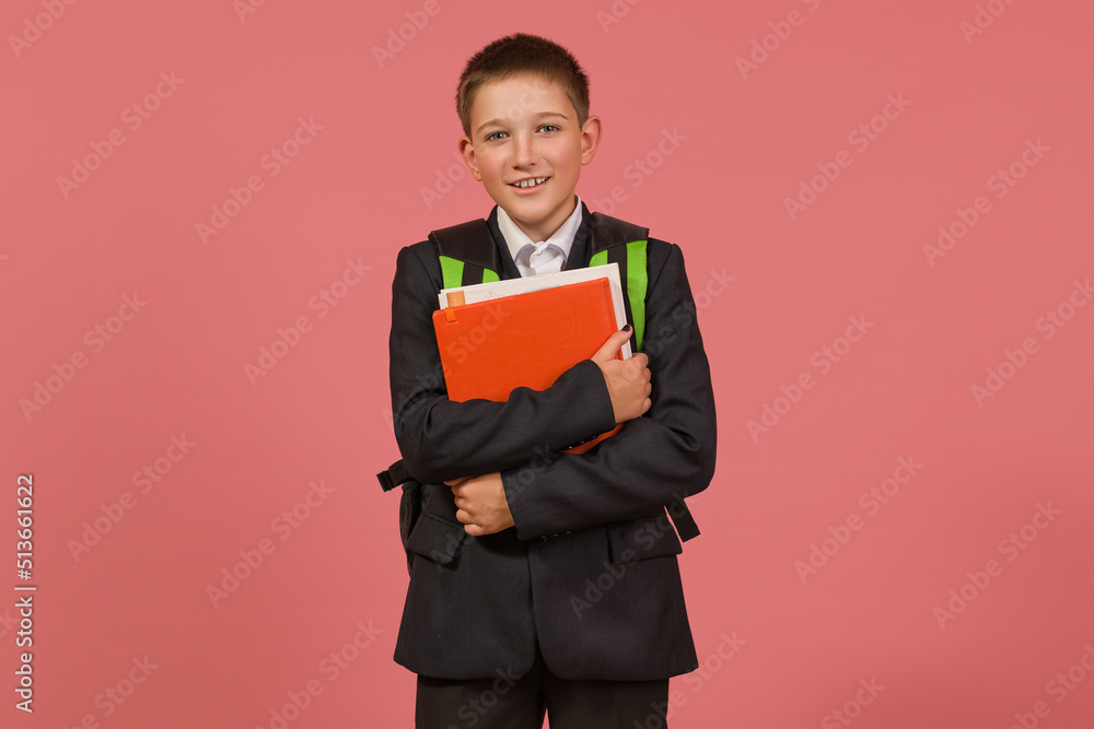 schoolboy in a black suit with a briefcase hugging books on a colored background schoolboy in a black suit with a briefcase hugging books on a colored background