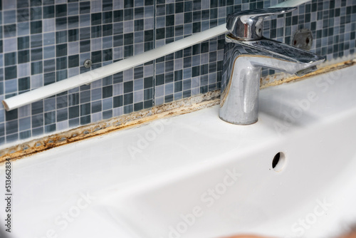 plumber removing old silicone from bathroom sink photo