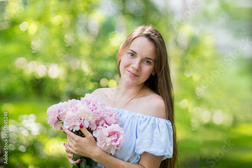 Young woman smiling behind pink peony flower