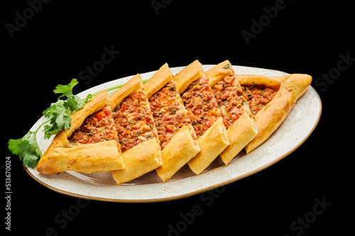 turkish pizza pide with minced meat lies on a plate on a black isolated background