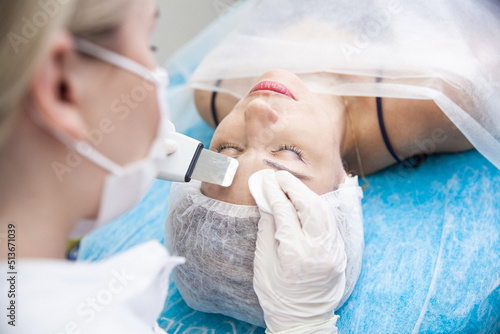 Print op canvas A cosmetologist in white gloves performs care procedures for a woman using an ul