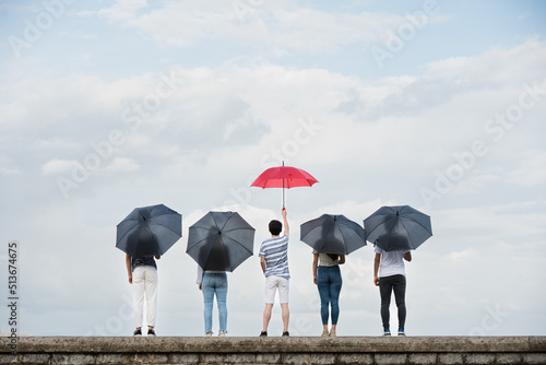 Standing out from crowd and leadership concept. Rear view of people standing and holding umbrellas photo