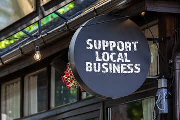 Support local business. Round, black sign onn teh wall of the house