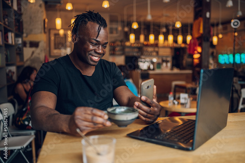 African american man using laptop while drinking coffee in a cafe