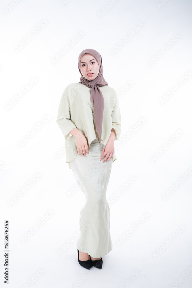 Fototapeta premium Beautiful female model in poses wearing traditional apparel and hijab, an urban lifestyle look for Muslim women isolated on white background. Beauty and hijab fashion concept. Full length