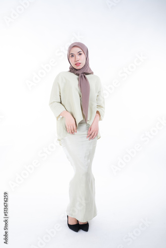 Beautiful female model in poses wearing traditional apparel and hijab, an urban lifestyle look for Muslim women isolated on white background. Beauty and hijab fashion concept. Full length