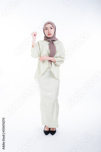 Beautiful female model in poses wearing traditional apparel and hijab, an urban lifestyle look for Muslim women isolated on white background. Beauty and hijab fashion concept. Full length