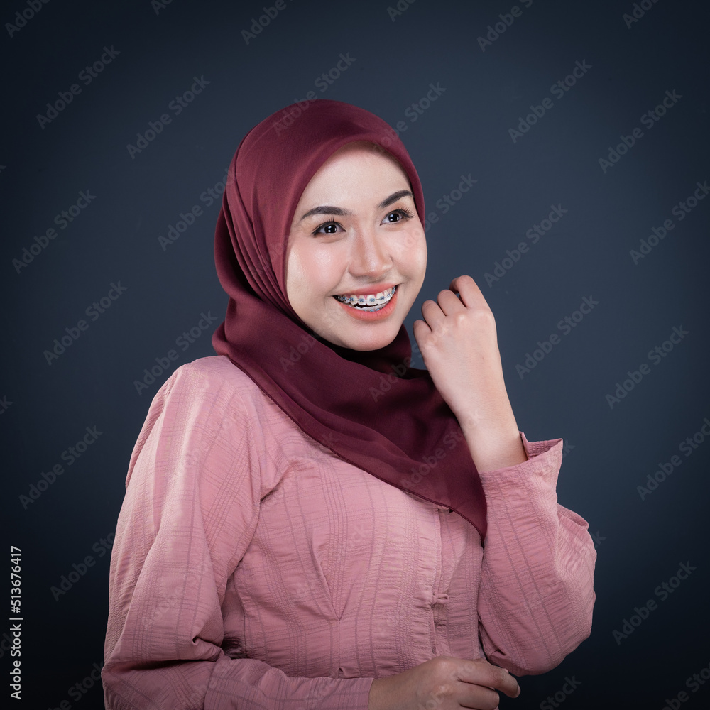 Close up portrait of a beautiful female model wearing traditional dress and hijab, a lifestyle apparel for Muslim women isolated on grey background. Idul Fitri and hijab fashion concept. Close up portrait of a beautiful female model wearing traditional dress and hijab, a lifestyle apparel for Muslim women isolated on grey background. Idul Fitri and hijab fashion concept.