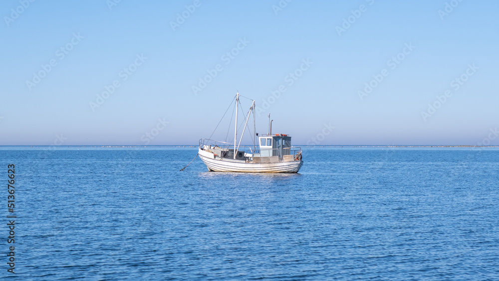 Small white fishing boat floating in the Baltic sea - fisherman out to sea to support his family.