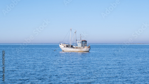 Small white fishing boat floating in the Baltic sea - fisherman out to sea to support his family.