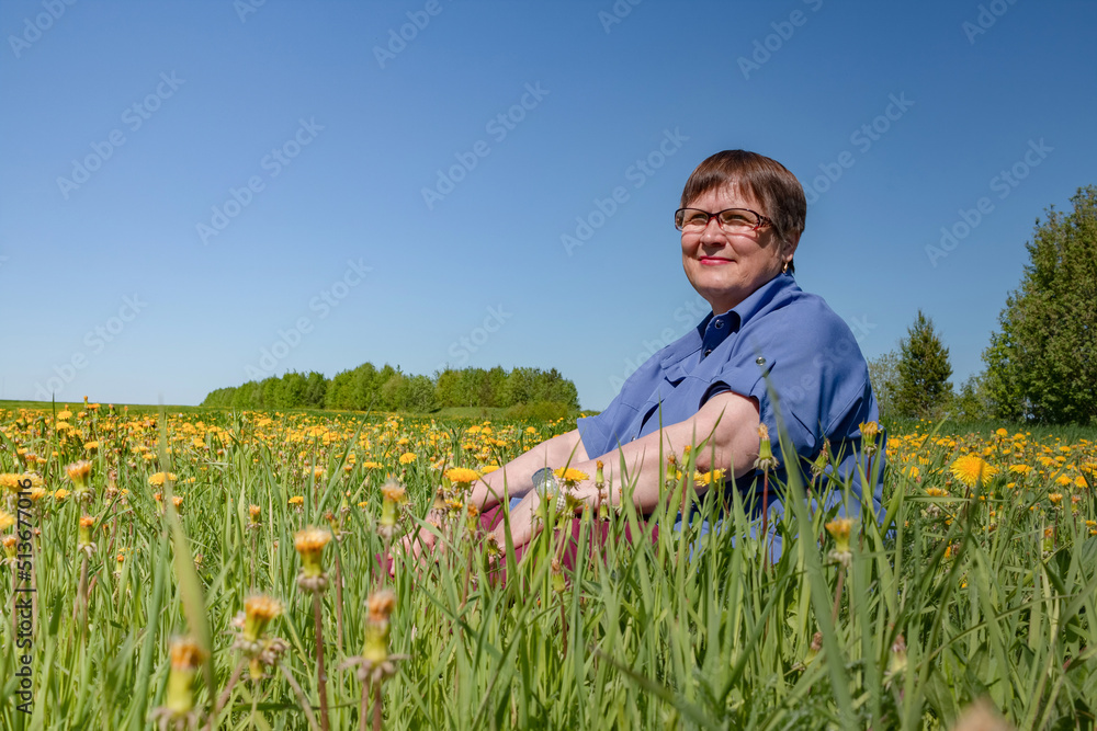 An elderly woman sits in a field. An elderly woman sits in a field.