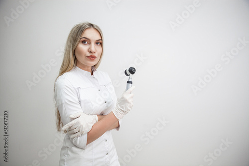 Portrait of blonde woman dermatologist with dermatoscope in white lab coat and white gloves on the white background photo