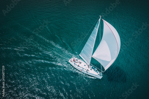 Regatta sailing ship yachts with white sails at opened sea. Aerial view of sailboat in windy condition © ValentinValkov