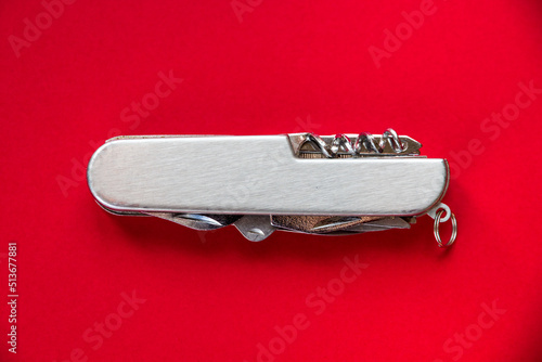 Foto Metallic swiss knife isolated on red