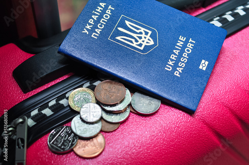 Ukrainian international passport pences and pink travel bag of refugee. photo