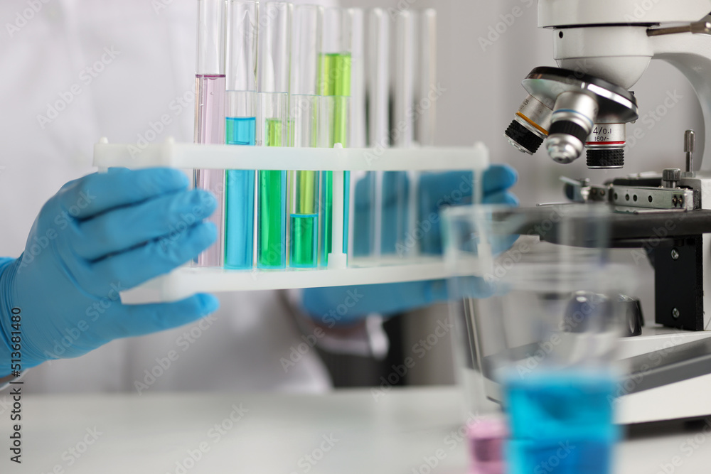 Fototapeta premium Scientist is holding test tubes with blue green liquids in laboratory
