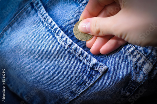 hand puts gold coin change in jeans pocket .Savings concept 