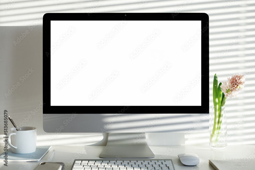 Technology, communication and remote job concept. Front view of nice workplace of female copywriter with fresh flowers, glass of water and generic desktop computer with blank display for your content Technology, communication and remote job concept. Front view of nice workplace of female copywriter with fresh flowers, glass of water and generic desktop computer with blank display for your content