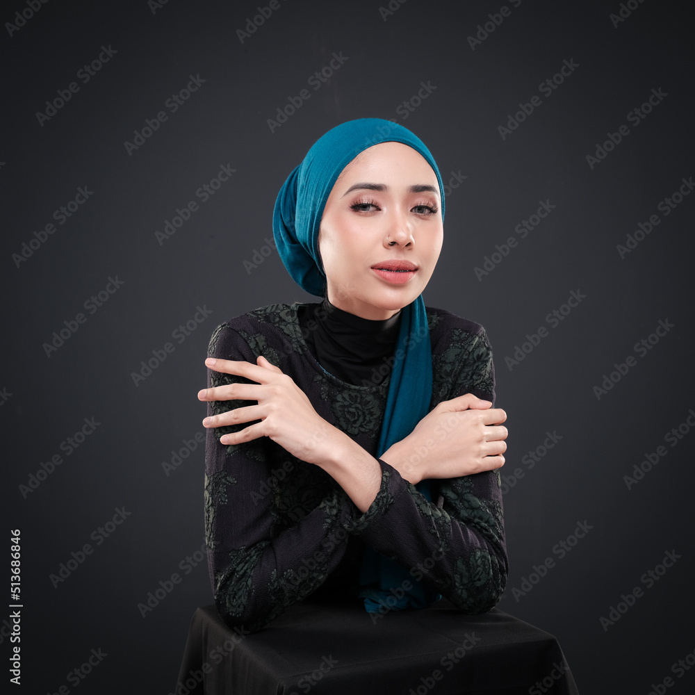 Half height portrait of a beautiful female model wearing traditional dress and hijab, a lifestyle apparel for Muslim women isolated on grey background. Idul Fitri and hijab fashion concept. Half height portrait of a beautiful female model wearing traditional dress and hijab, a lifestyle apparel for Muslim women isolated on grey background. Idul Fitri and hijab fashion concept.