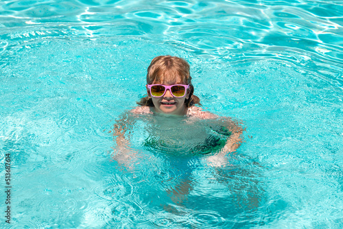 Child swim in poolside in water background. Happy child playing in swimming pool. Summer kids vacation.