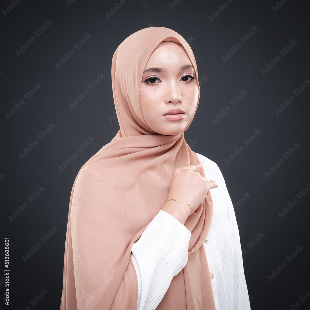 Half height portrait of a beautiful female model wearing traditional dress and hijab, a lifestyle apparel for Muslim women isolated on grey background. Idul Fitri and hijab fashion concept. Half height portrait of a beautiful female model wearing traditional dress and hijab, a lifestyle apparel for Muslim women isolated on grey background. Idul Fitri and hijab fashion concept.