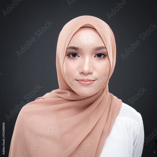 Half height portrait of a beautiful female model wearing traditional dress and hijab, a lifestyle apparel for Muslim women isolated on grey background. Idul Fitri and hijab fashion concept.
