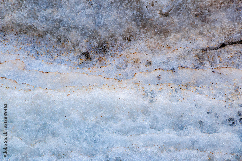 Fototapeta premium Cracks on thick ice on surface of frozen river in winter season, powdered by snow and sand, with brilliant snow and ice crystals.