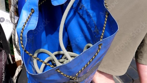 Close up of blue bag by the leg of man who is pulling mountaineering rope from it during abseiling training from the bridge in Peak District National Park, United Kingdom.