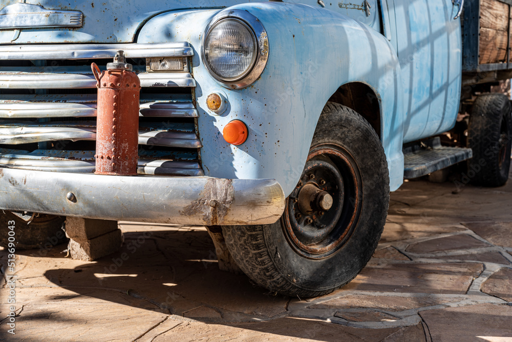 Fototapeta premium A light blue vintage american car with a fire extinguisher on top of its bumper