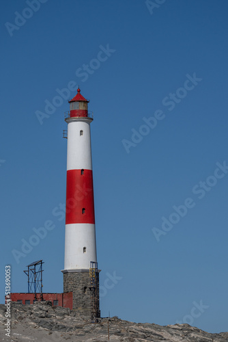 A white and red lighthouse in front of a blue sky at Diaz Point near L  deritz in Namibia