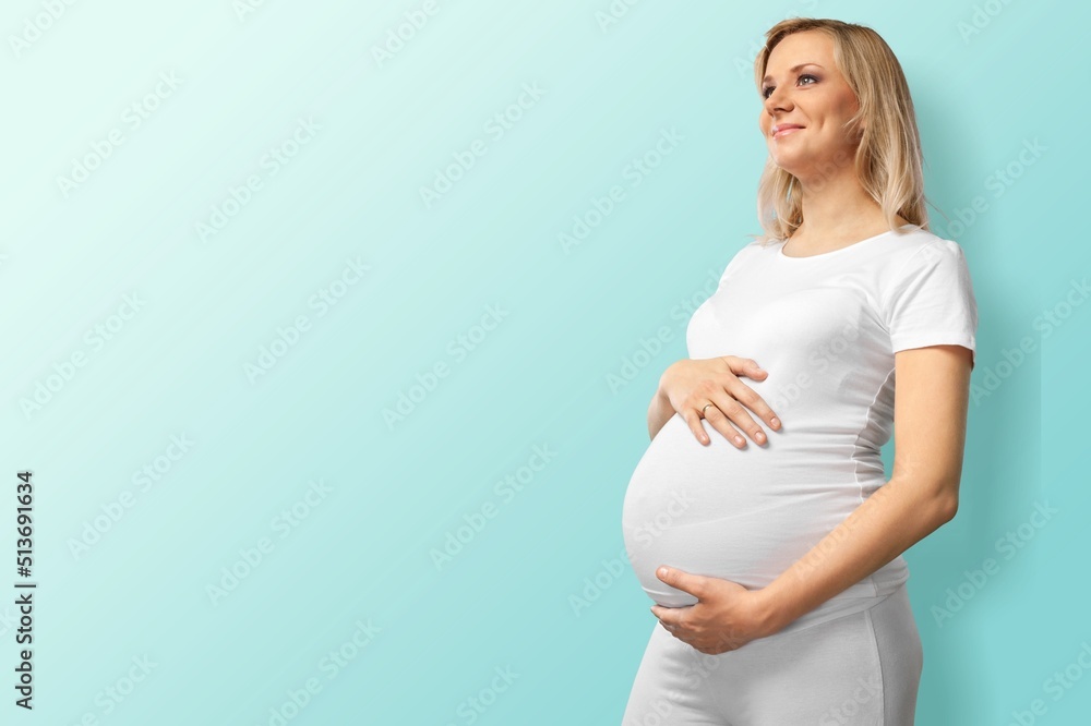 Pregnant Woman holds her belly. Healthy Pregnancy concept. Sitting Gravid female on blue background, full length portrait Pregnant Woman holds her belly. Healthy Pregnancy concept. Sitting Gravid female on blue background, full length portrait