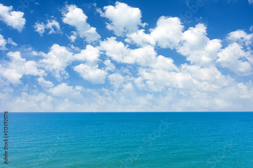 View of the sea surface and the horizon. Summer fluffy clouds over the ocean in tropical latitudes. Concept of summer vacation, travel.