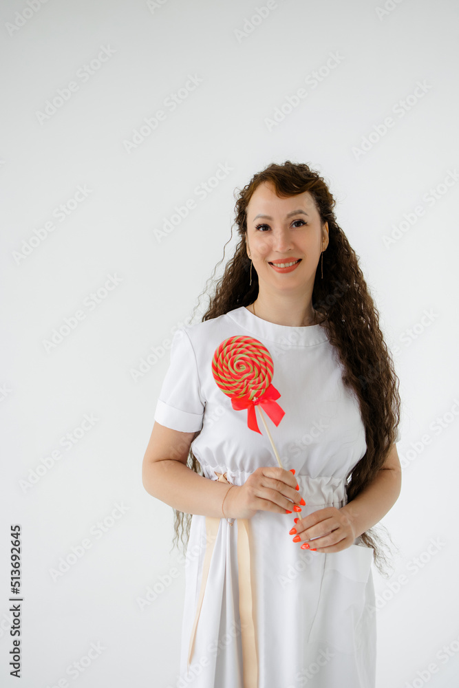 Portrait of a girl working as a doctor with a sugar lollipop in her hands, isolated white background. cosmetologist, beauty industry or children's doctor. Salon care and rejuvenation concept. 
