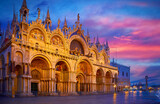 Venice, Italy. Basilica of Saint Mark and Clocktower on Piazza San Marco square. Evening cityscape with street Lamps illumination. Famous Landmark in Venice, basilica di san marco Scenic sunset view.